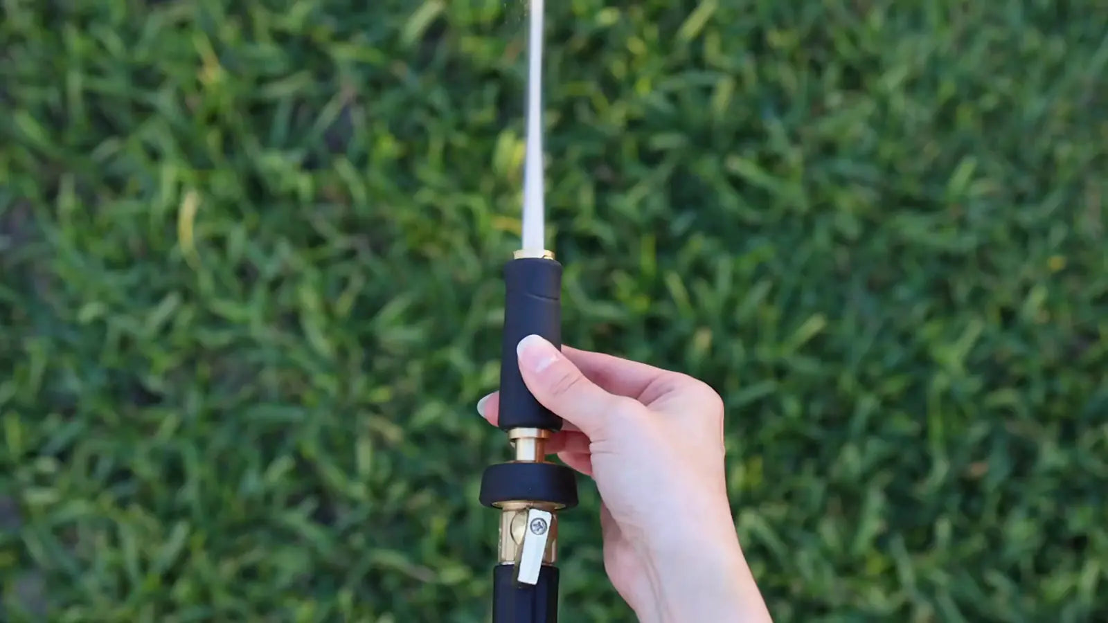 Titan hose spraying a wide fan of water across a hedge